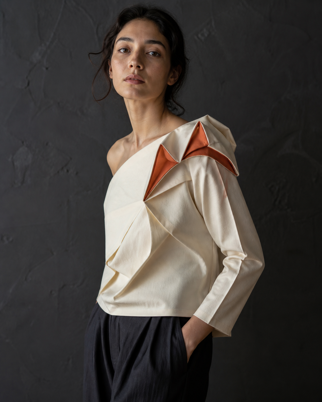 Modelo com Fold Blouse marfim de dobras escultóricas e acentos terracota